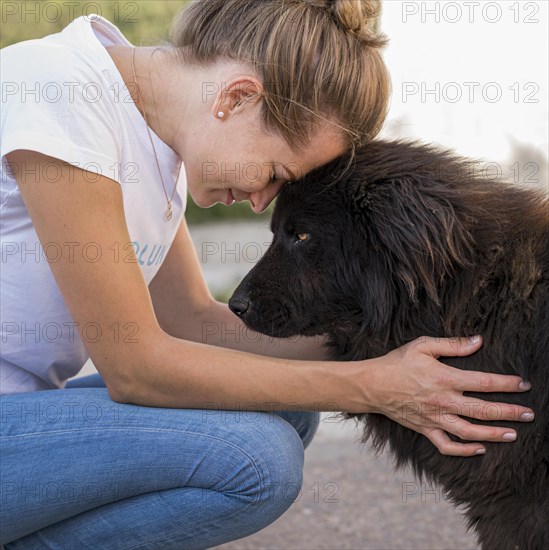 Side view woman with fluffy black dog outdoors