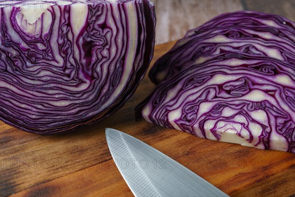 Sliced red cabbage on a wooden board with a knife in the foreground