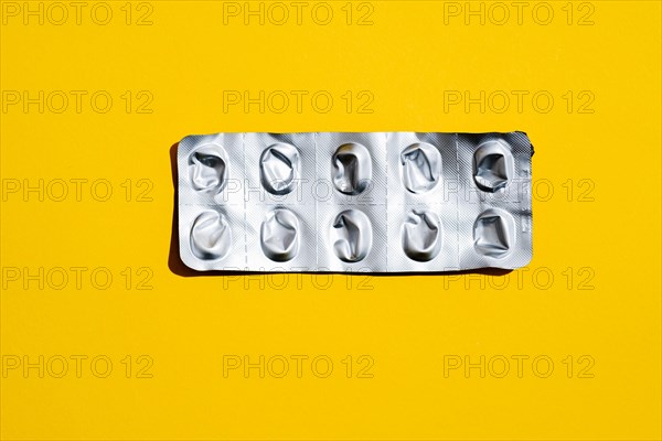 Empty tablet blister pack against yellow background