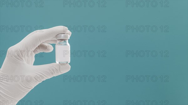 Vaccine bottle held by hand with glove