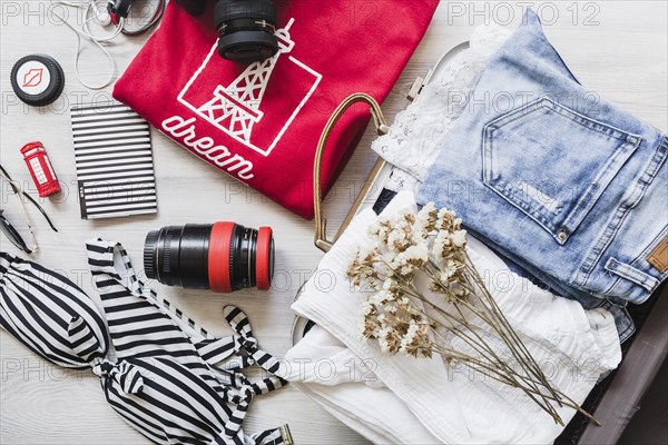 Overhead view travelling bag with female outfits flowers