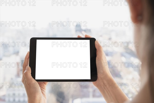 Hands holding tablet with defocused background