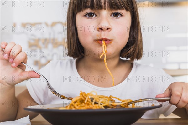 Cute girl eating delicious pasta kitchen