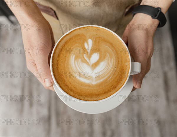 Top view female barista holding decorated cup coffee hands
