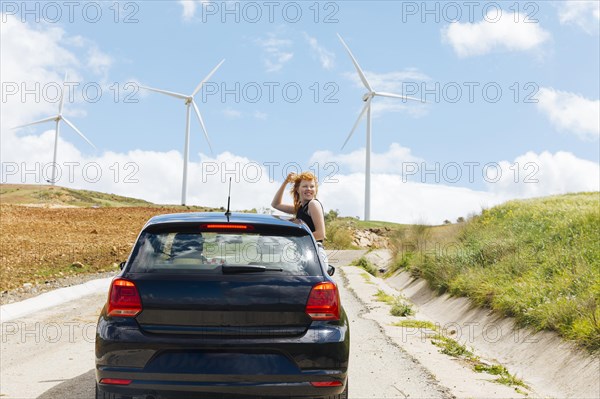 Woman looking back road out car window