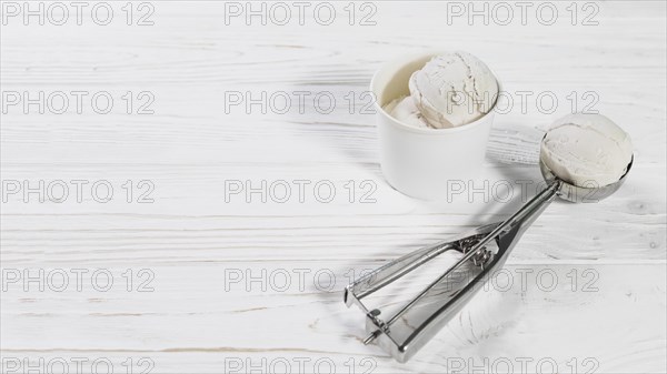 Scoop with ice cream ball near cup