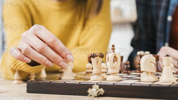 Close up young woman playing chess board game