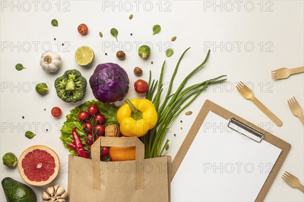 Top view assortment vegetables paper bag with clipboard