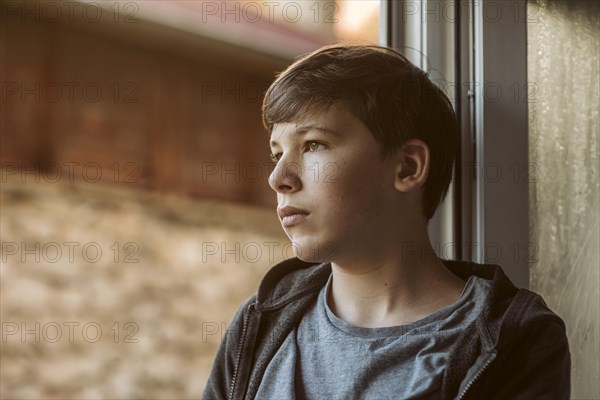 Side view sad boy looking outside