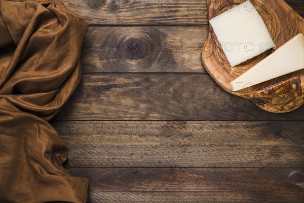 Tasty cheese wooden cheese board with brown silk fabric old wooden surface