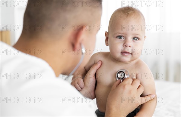 Back view doctor listening little baby with stethoscope
