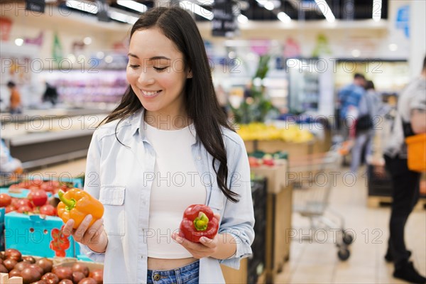 Cheerful woman choosing bell pepper grocery store