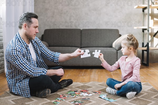 Father daughter hand holding jigsaw puzzle piece