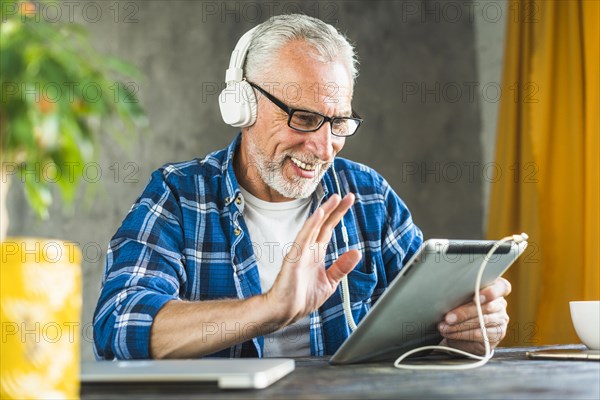 Smiling senior man saying hello digital tablet