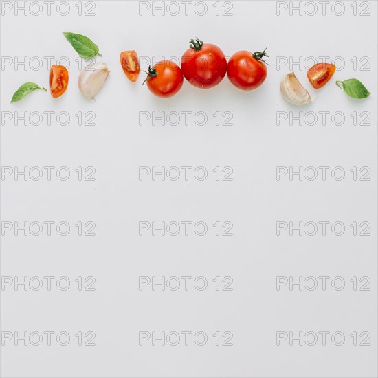 Whole slice cherry tomatoes garlic clove basil white background