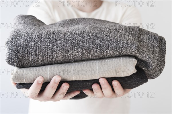 Front view person holding stacked laundry