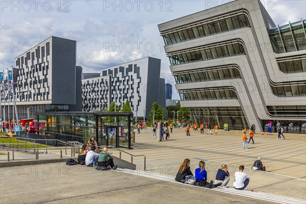 Students in front of modern buildings on the campus of the University of Economics WU