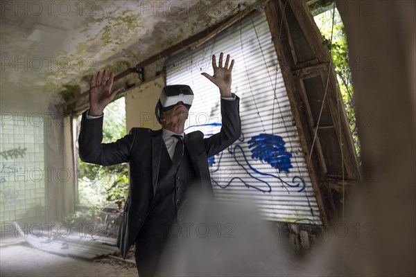 Man dressed in suit wearing VR glasses in a dilapidated office building