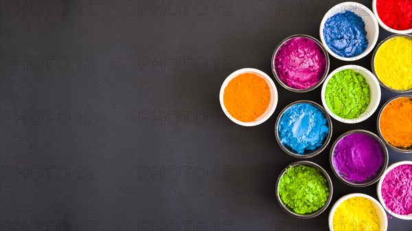 Overhead view bowls color holi powder black backdrop