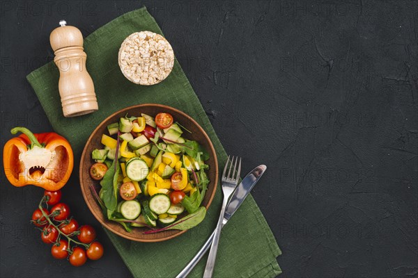 Rice puffed cake vegetables salad pepper shakers napkin black concrete textured backdrop