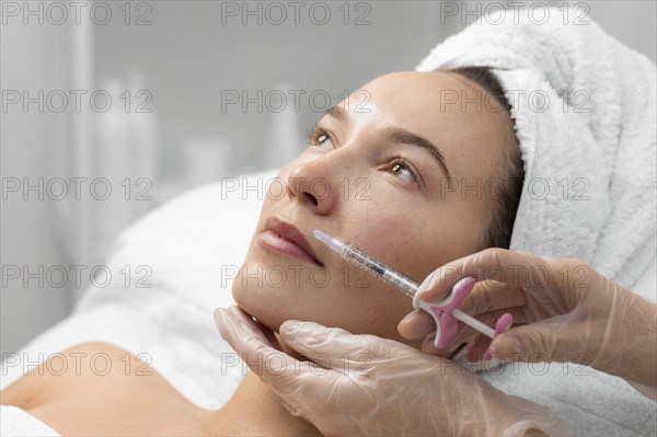 Beautician doing filler injection female client