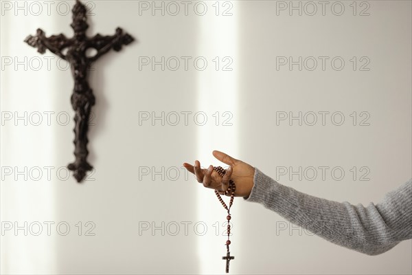 Religious woman praying with rosary beads home