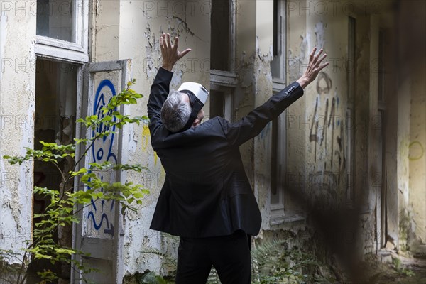 Man dressed in suit wearing VR glasses in a dilapidated office building