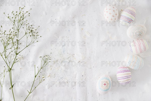 Row easter eggs with patterns near plant twig feathers textile
