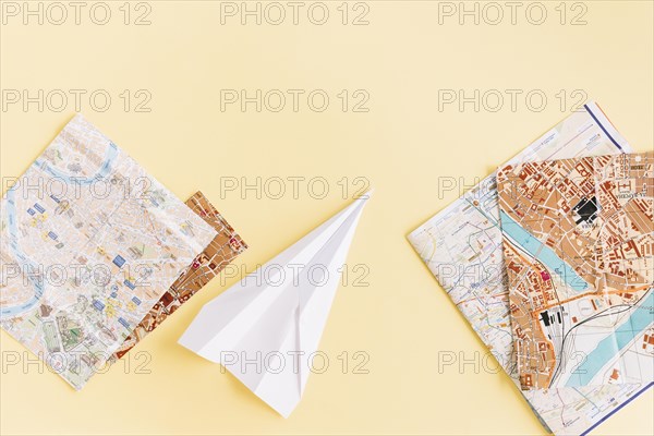 Variety maps with white paper airplane beige background