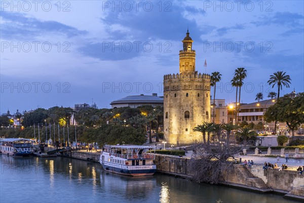 On the banks of the Guadalquivir River with the historic Torre del Oro tower at dusk