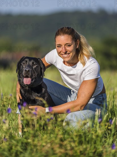 Portrait of a woman and a Labrador dog on a meadow