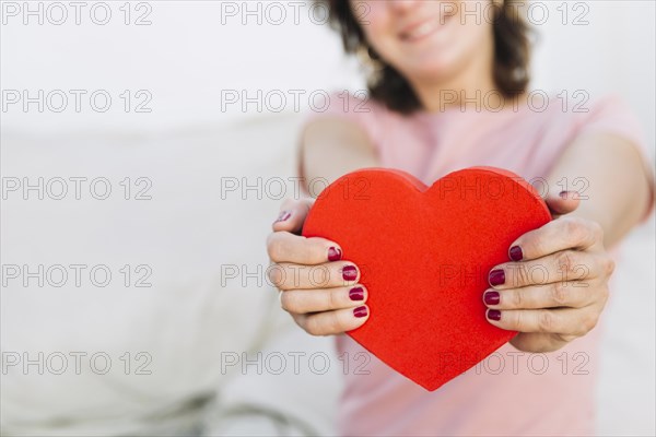 Crop woman showing heart shaped box