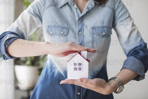 Midsection woman protecting house model office