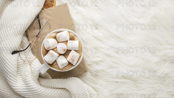 Top view cup hot marshmallows glasses book