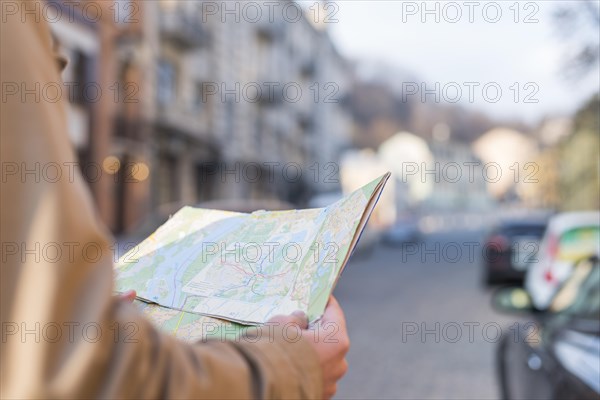 Close up male traveler holding map hand standing city street