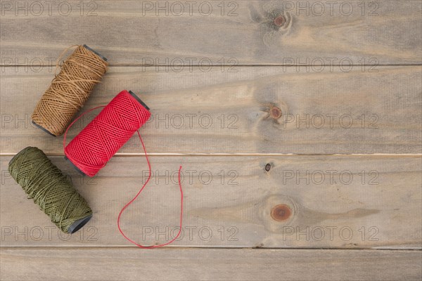 Red brown green yarn spool wooden table