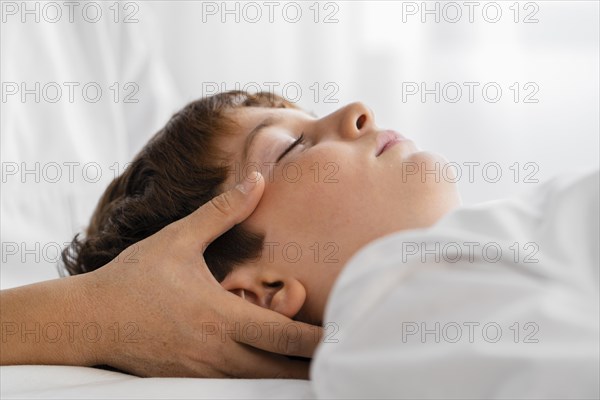 Female osteopathist treating child by massaging his head