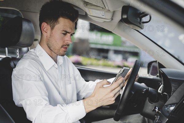 Side view young handsome man using cell phone car