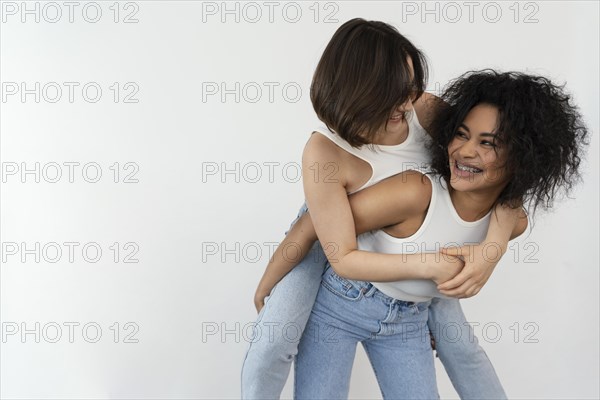 Young girlfriends enjoying time together with piggy back ride