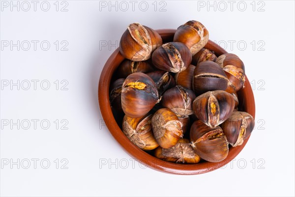 Roasted chestnuts in an earthenware casserole isolated on a white background