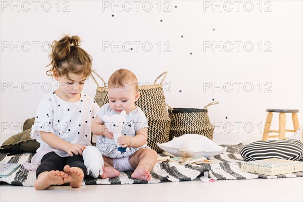 Sibling playing with toys striped rag