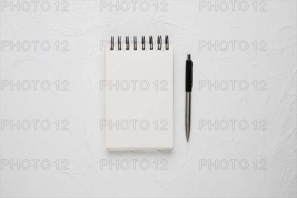 High angle view white blank spiral notepad with ballpoint pen