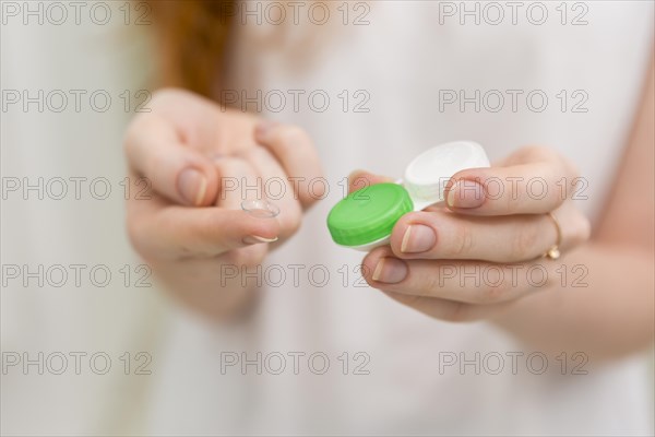Woman hand holding contact lens it s container