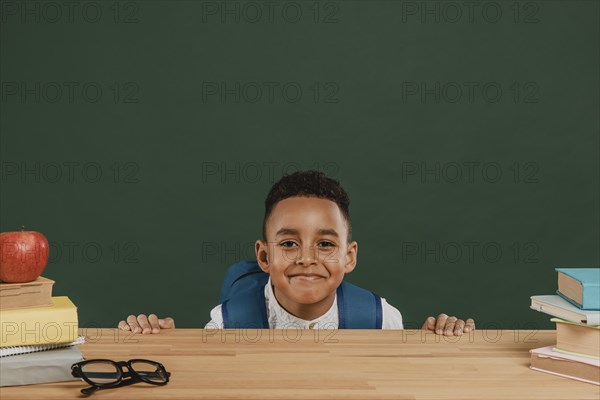 Cute boy with backpack hiding table