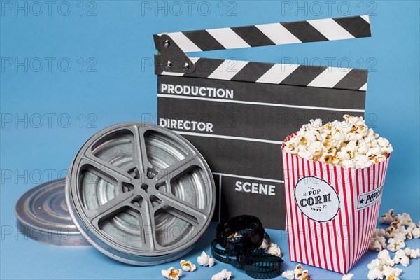 Film reels film strips clapperboard with popcorn box blue background