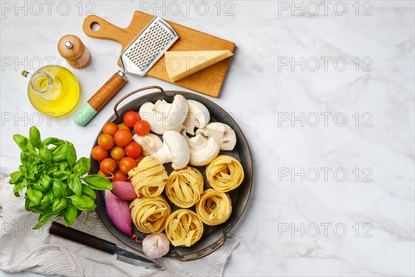 Top view of raw ingredients for mushroom pasta on marble background