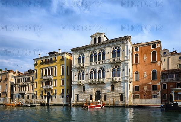 Beautiful view of Venetian landscape. Colorful waterfront palace or palazzo of Renaissance era and a boat moored by it. Grand Canal