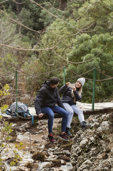 Couple with backpack sitting bridge 1