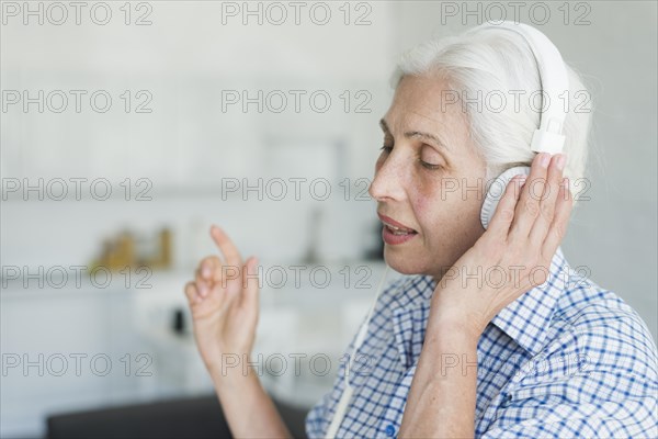 Side view senior woman listening music headphone singing