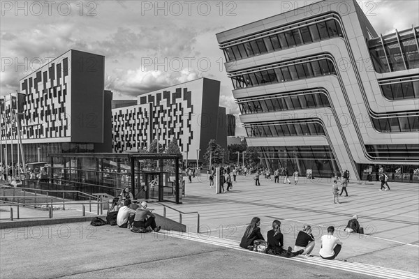 Students in front of modern buildings on the campus of the University of Economics WU